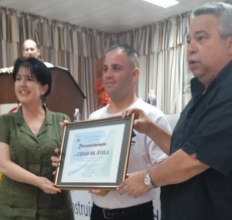 El joven sindicalista avileño Yuniel Espinosa Reyes (al centro) recibe el reconocimiento otorgado a la provincia de Ciego de Ávila como destacada en la Jornada Nacional de Seguridad y Salud en el Trabajo. Foto: Sulema Véliz Pina